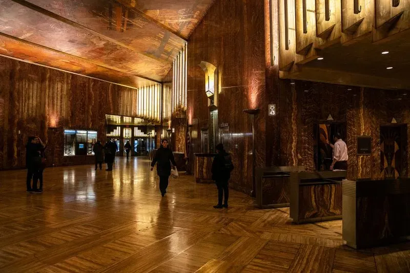 مدخل مبنى كرايسلر في نيويورك، يظهر التصميم الأنيق والعناصر المعمارية لأسلوب آرت ديكو، مع تفاصيل من الرخام والإضاءة المميزة.