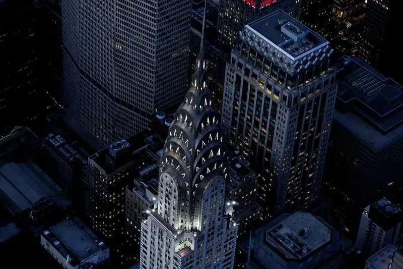 مبنى كرايسلر في نيويورك، مع تصميمه الفريد في أسلوب الآرت ديكو، يتألق ليلاً بأضواءه المميزة، محاطاً بناطحات السحاب الأخرى.