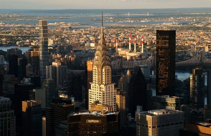 مبنى كرايسلر، رمز فن الآرت ديكو في نيويورك، يظهر بوضوح في الأفق، مع تصميمه الفريد وارتفاعه المذهل، محاطاً بناطحات السحاب الحديثة.