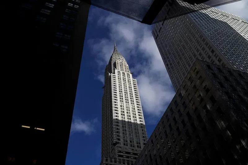 مبنى كرايسلر في مانهاتن، رمز فن الآرت ديكو، يتألق بارتفاعه البالغ 1046 قدمًا، محاطًا بأبنية حديثة تحت سماء زرقاء.