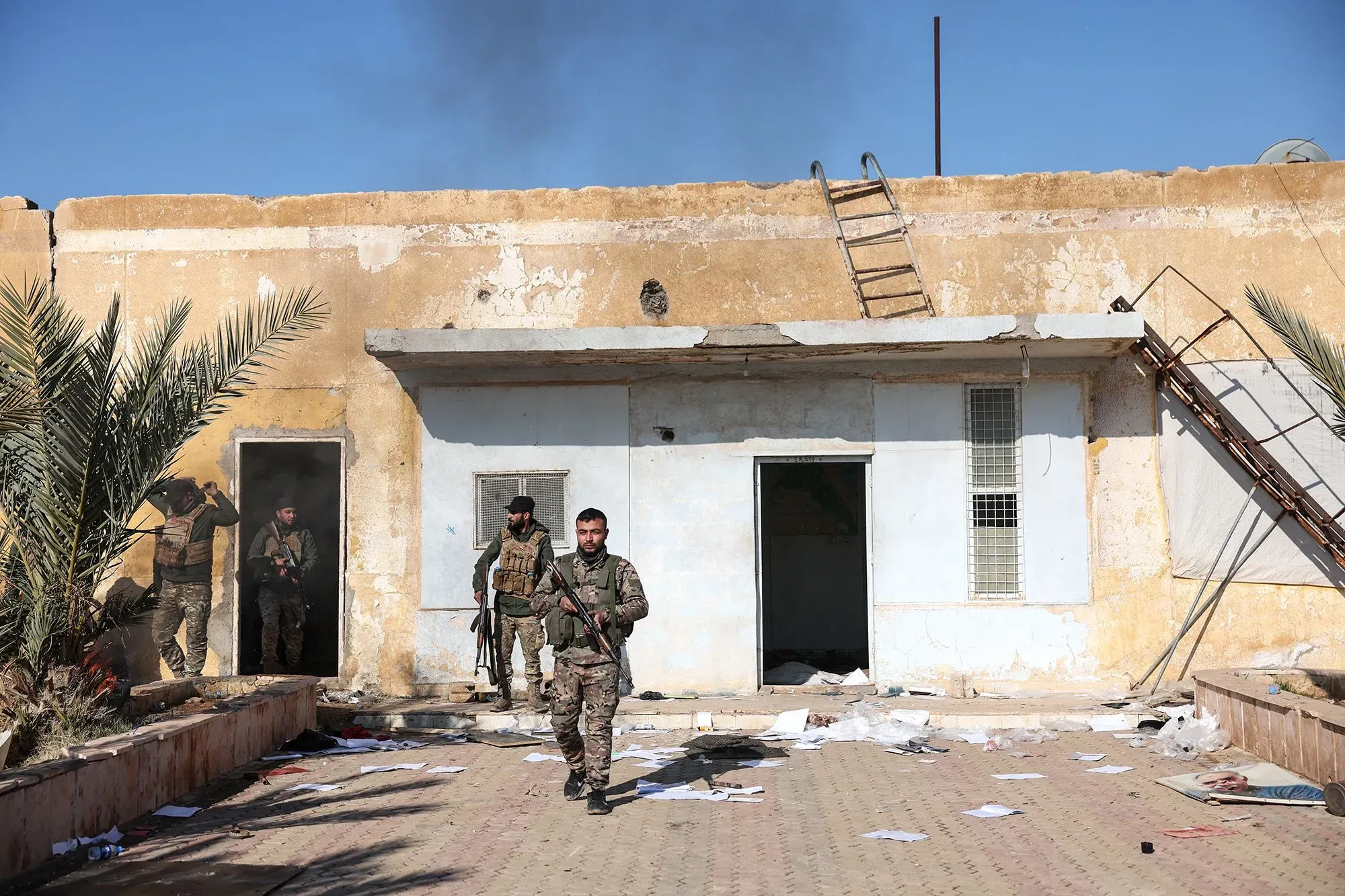 جنود من قوات سوريا الديمقراطية يتجولون في سجن الشدادي بعد استعادة القوات الحكومية السيطرة على المنطقة، وسط فوضى وأوراق متناثرة.