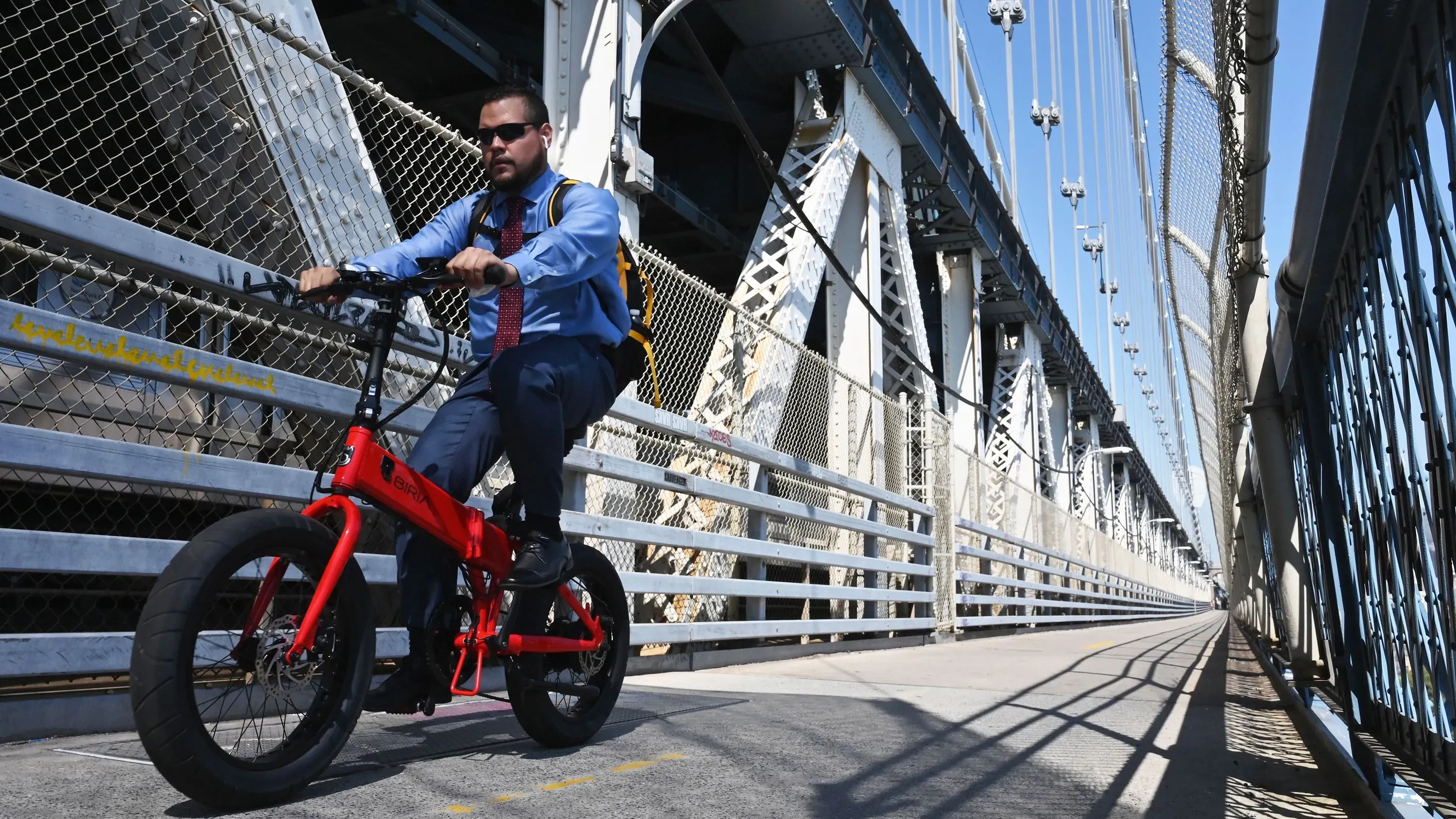 رجل يرتدي بدلة رسمية يركب دراجة حمراء على جسر، مما يعكس تأثير السياسات الجديدة على حوافز التنقل بالدراجات في الولايات المتحدة.