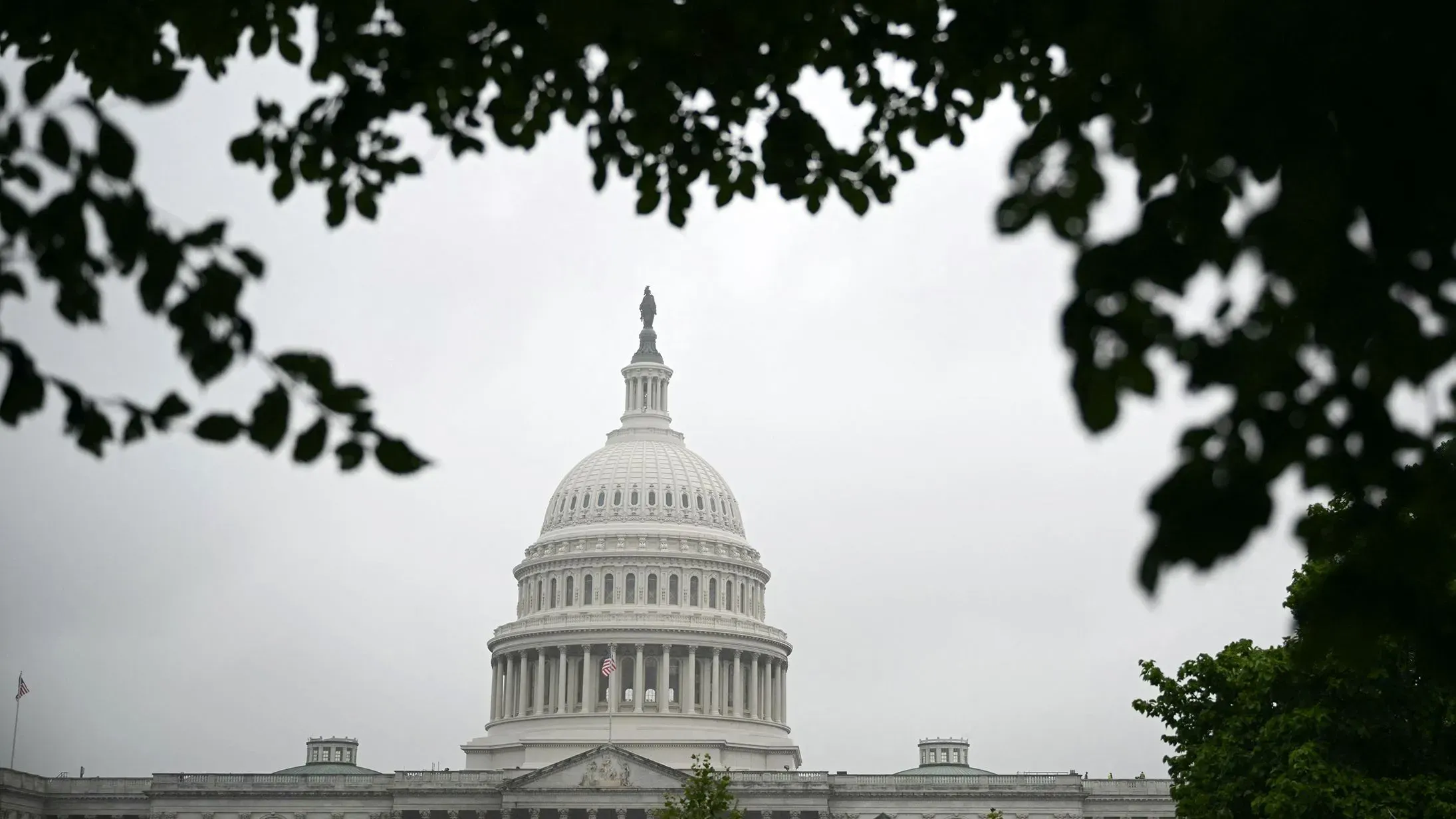 قبة مبنى الكابيتول الأمريكي محاطة بأشجار، تحت سماء غائمة، تعكس التركيز على التحديات التشريعية الراهنة في مجلس الشيوخ.