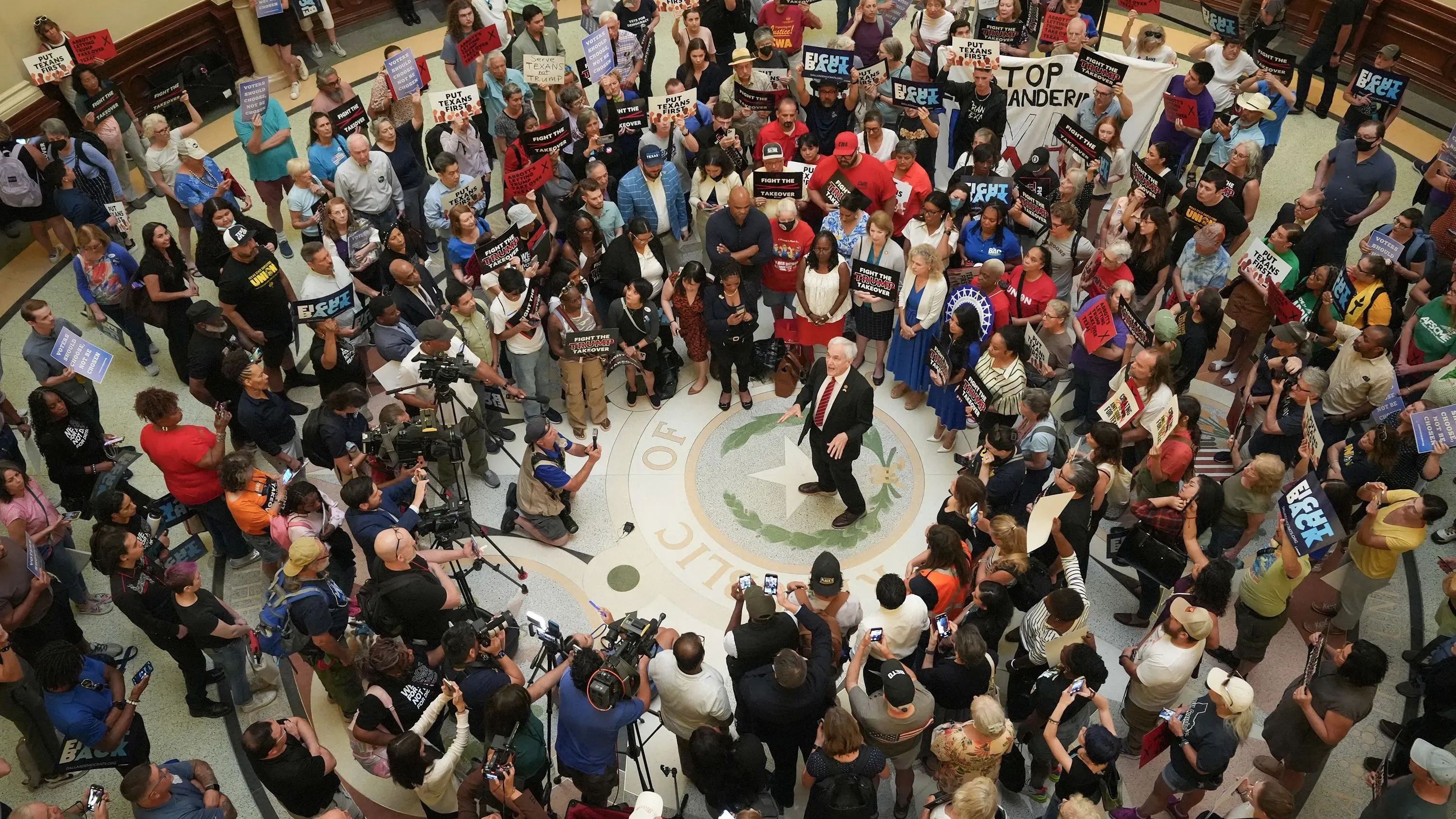 تجمع حاشد في مبنى حكومي بولاية تكساس، حيث يحمل المتظاهرون لافتات تعبر عن معارضتهم لإعادة تقسيم الدوائر الانتخابية.