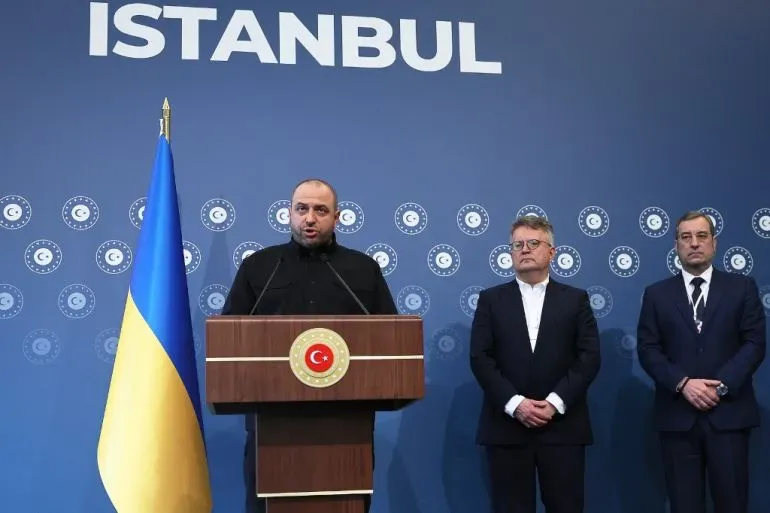 مؤتمر صحفي في إسطنبول يتحدث فيه ممثل أوكراني، مع علم أوكرانيا خلفه، وسط قادة آخرين، حول جهود السلام.