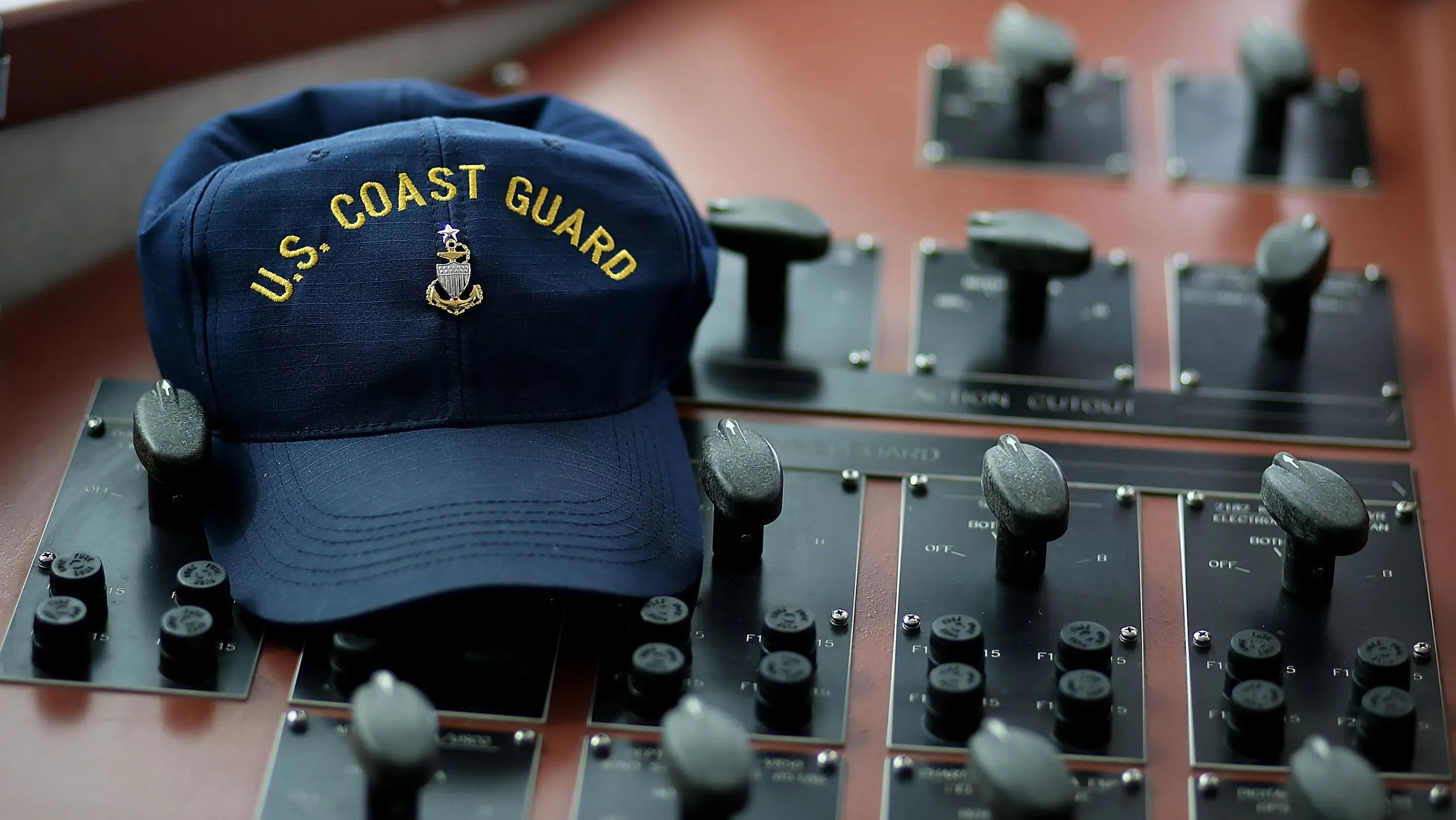 قبعة خفر السواحل الأمريكية موضوعة على لوحة تحكم، مما يعكس أهمية الأمن في القواعد البحرية في ظل اعتقال زوجة أحد أفراد الخدمة.