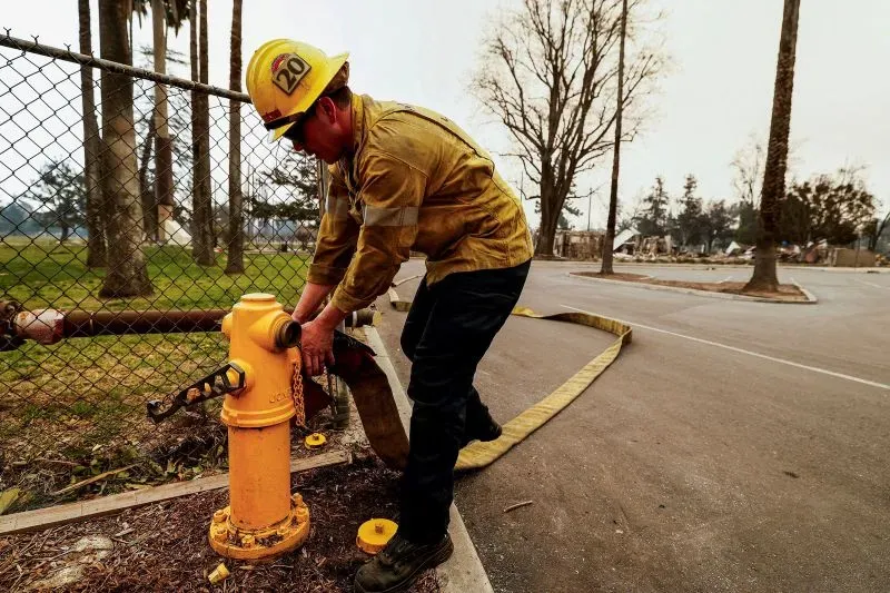 رجل إطفاء يقوم بفتح صنبور إطفاء في منطقة متضررة من حرائق الغابات بلوس أنجلوس، حيث تضررت أنظمة المياه بسبب الحرائق.