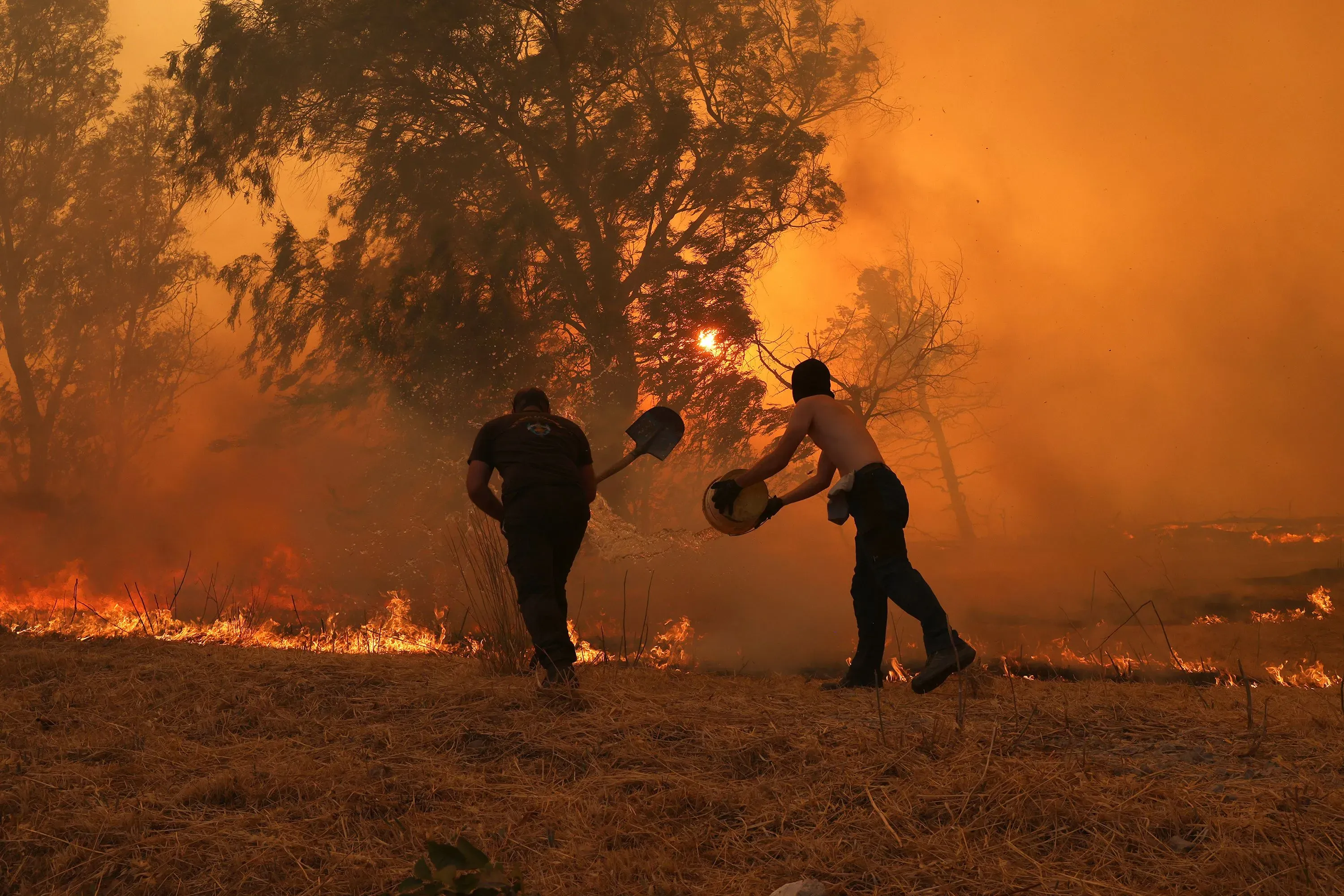 رجال إطفاء يكافحون حرائق الغابات في تركيا، حيث تتصاعد النيران والدخان في الأجواء، مما يشير إلى أزمة بيئية خطيرة.