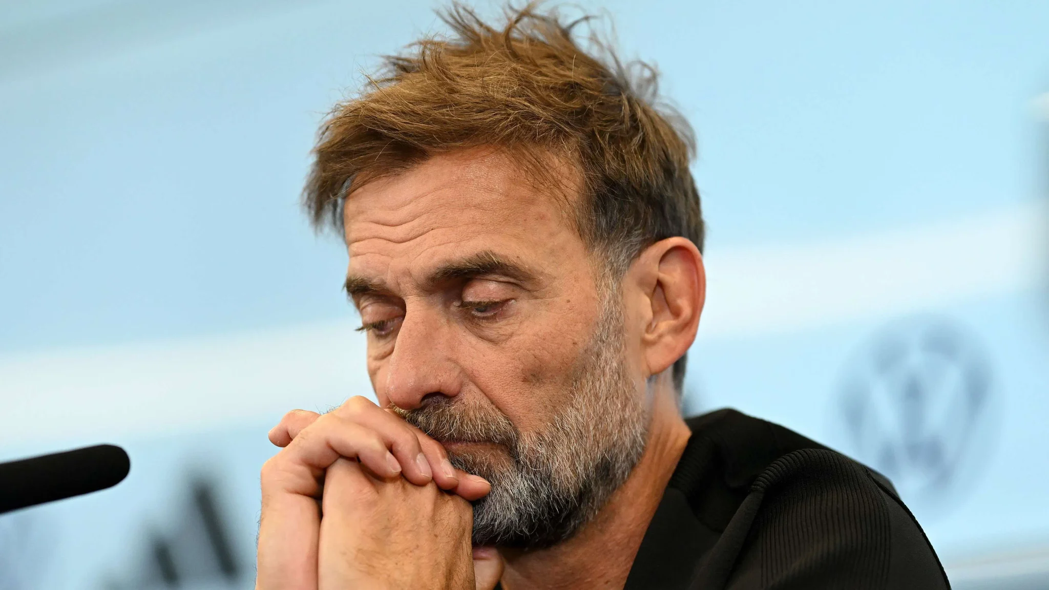 مدرب كرة القدم Roberto Mancini يبدو متأملاً وجاداً خلال مؤتمر صحفي، مع خلفية تحمل شعار الاتحاد الإيطالي لكرة القدم.