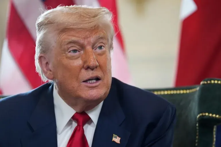 ترامب يتحدث خلال مؤتمر صحفي، مع خلفية الأعلام، معرباً عن تهديداته لإيران بسبب برنامجها النووي.