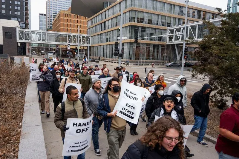 مظاهرة حاشدة في مدينة أمريكية، حيث يحمل المشاركون لافتات تدعو للدفاع عن الحقوق المدنية، وسط مبانٍ حديثة.