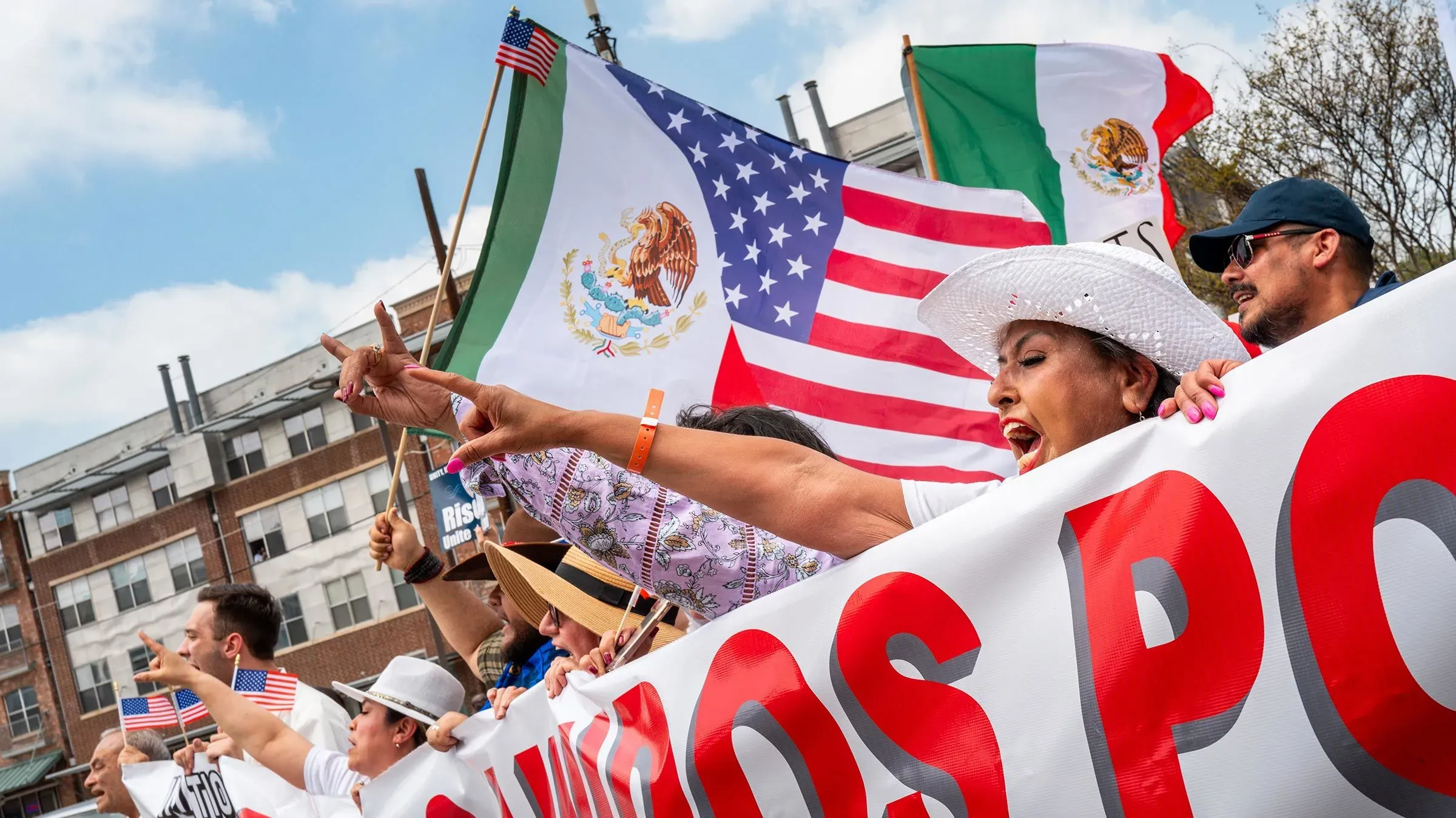 مظاهرة في دالاس تضم حشودًا كبيرة تحمل أعلام الولايات المتحدة والمكسيك، تعبر عن المطالب بالإصلاحات في سياسة الهجرة.