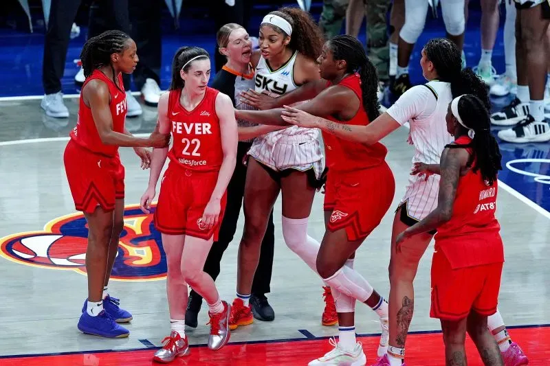 مشهد من مباراة كرة السلة بين شيكاغو سكاي وإنديانا فيفر، يظهر لحظة توتر بين اللاعبتين بعد تصادم، وسط اهتمام من زملاء الفريق والجمهور.