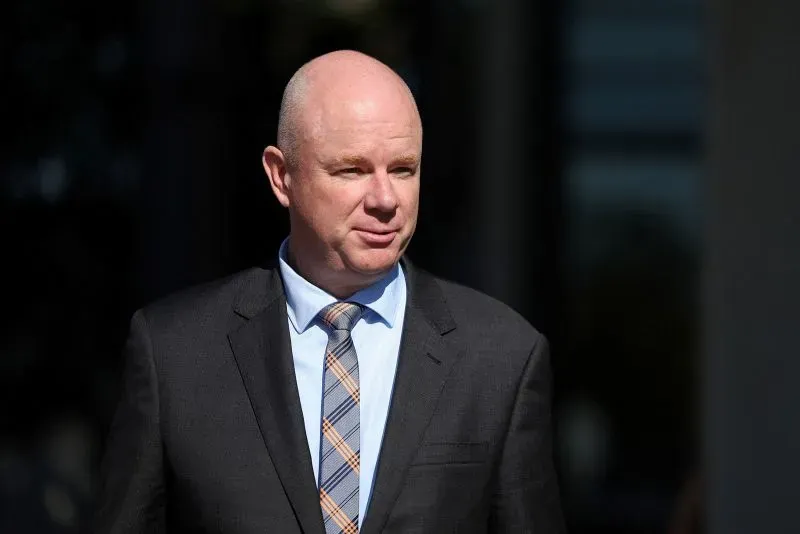 رجل يرتدي بدلة رسمية وقميصًا بألوان متناسقة، يظهر وهو يغادر المحكمة، في سياق محاكمة إيرين باترسون المتهمة بقتل ثلاثة أشخاص.