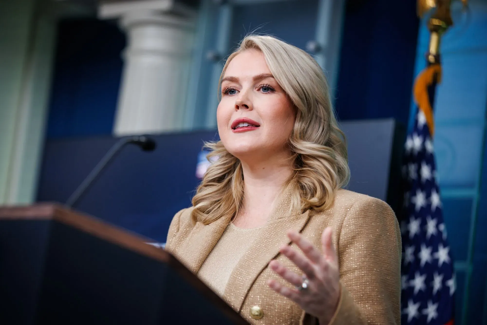 امرأة تتحدث في مؤتمر صحفي، ترتدي سترة ذهبية، مع العلم الأمريكي خلفها. تتعلق القضية بإفراجها بكفالة بعد اعتقالها من إدارة الهجرة.