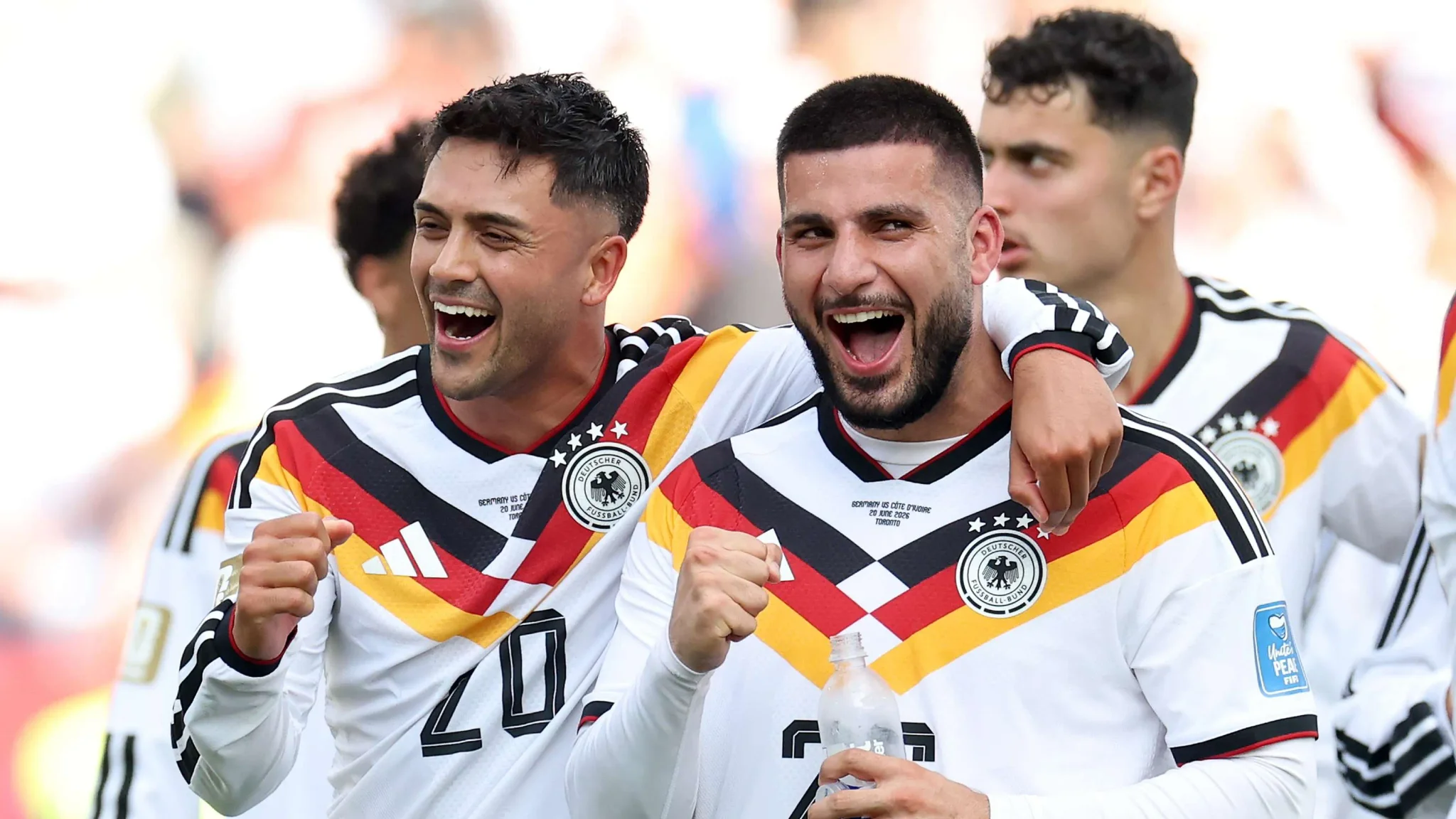 لاعبا منتخب ألمانيا يحتفلان بحماس خلال مباراة في كأس العالم 2026، مرتدين زي الفريق الرسمي بألوان العلم الألماني.