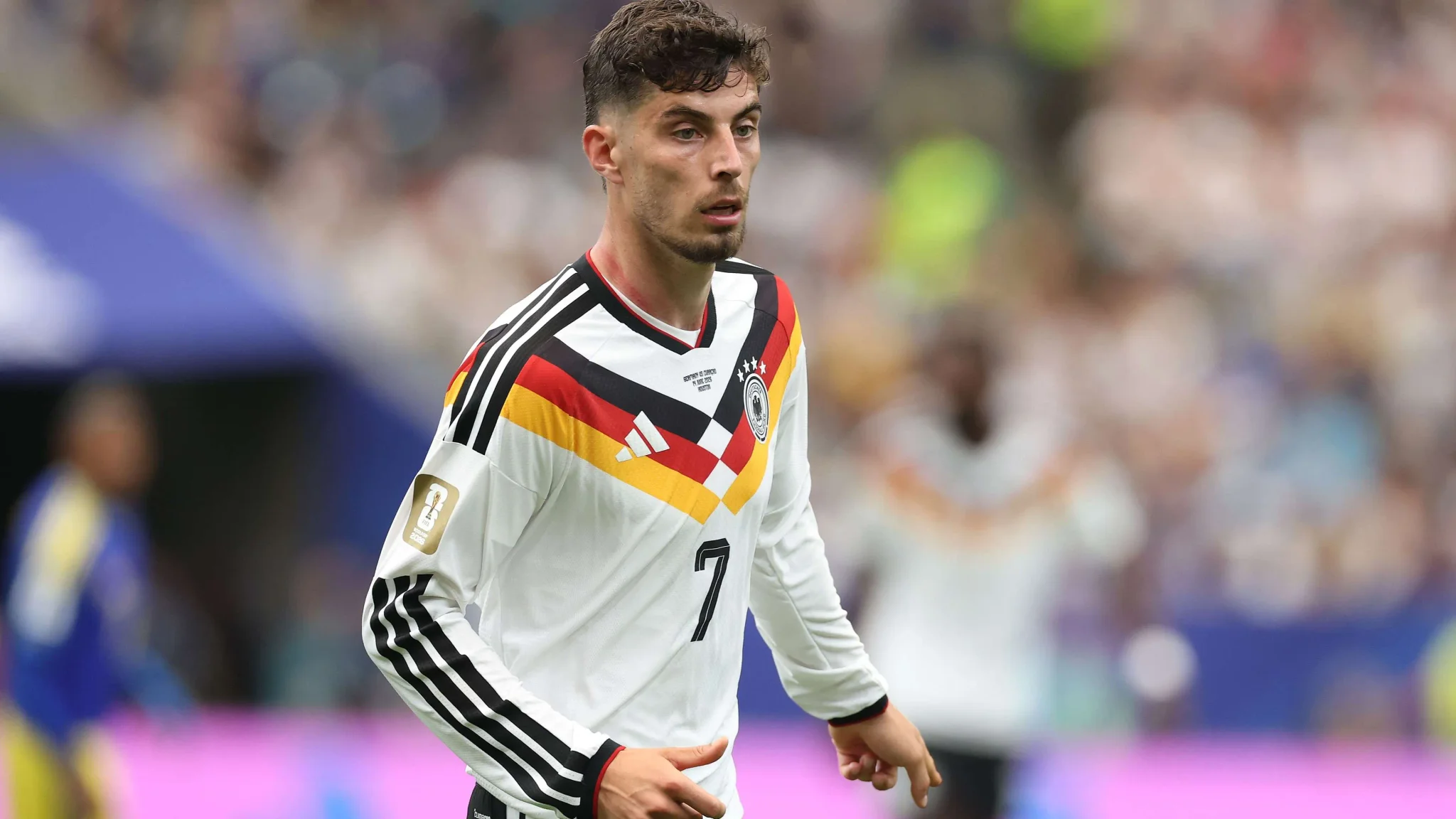 لاعب كرة قدم ألماني يرتدي قميص منتخب ألمانيا رقم 7 خلال مباراة في كأس العالم 2026، يركز على الكرة وسط أجواء حماسية في الملعب.