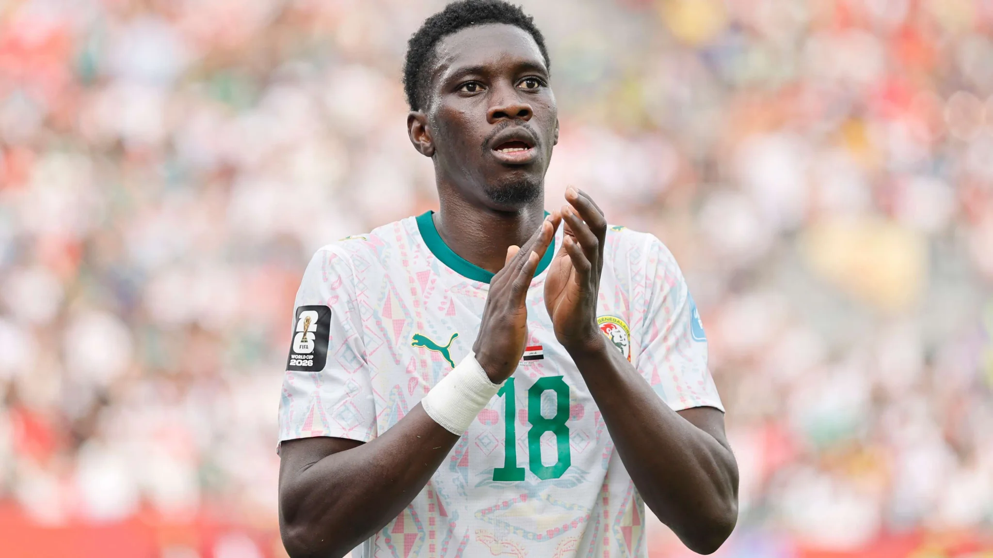 لاعب كرة قدم من السنغال يرتدي قميص المنتخب رقم 18 يصفق خلال مباراة كأس العالم 2026 في أمريكا الشمالية.
