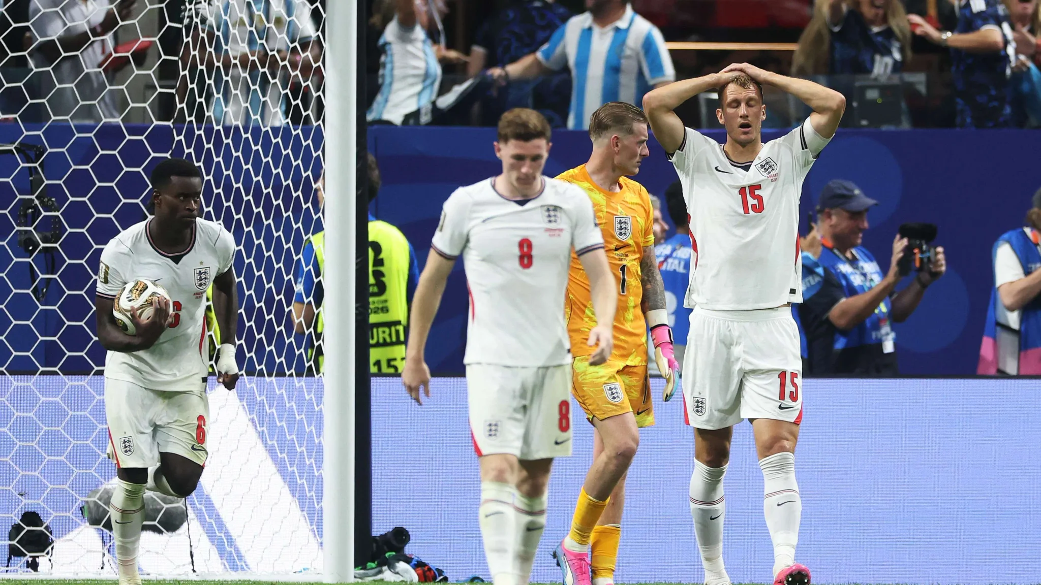 لاعبو منتخب إنجلترا يظهرون علامات الإحباط بعد هدف الأرجنتين في نصف نهائي بطولة كرة القدم، مع حارس المرمى واللاعبين في خلفية الملعب.