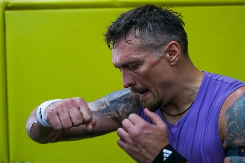 أولكسندر أوسيك، بطل العالم في الوزن الثقيل، يتدرب في صالة رياضية، مع التركيز على تدريباته في أجواء تعكس ارتباطه بأوكرانيا.