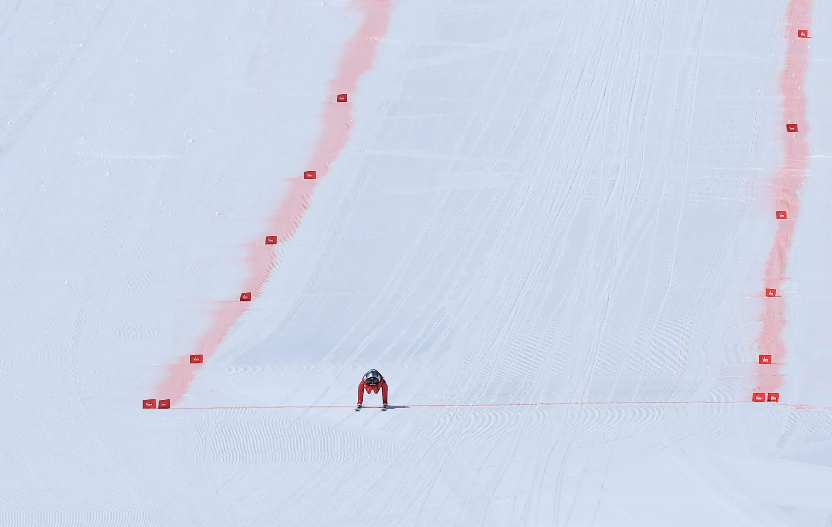 سيمون بيلي يتزلج بسرعة على منحدر ثلجي، مرتديًا بدلة حمراء وزي دارث فيدر، محاطًا بعلامات حمراء تحدد المسار.