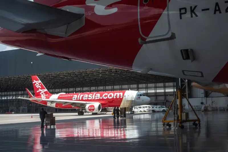 طائرة تابعة لشركة AirAsia في حظيرة الطائرات، مع طائرة أخرى في الخلفية، تعكس الابتكار والتطور في صناعة الطيران.