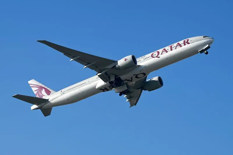 طائرة الخطوط الجوية القطرية من طراز بوينج 777-9 تحلق في السماء، تعكس إنجازات الناقلة في صناعة الطيران.