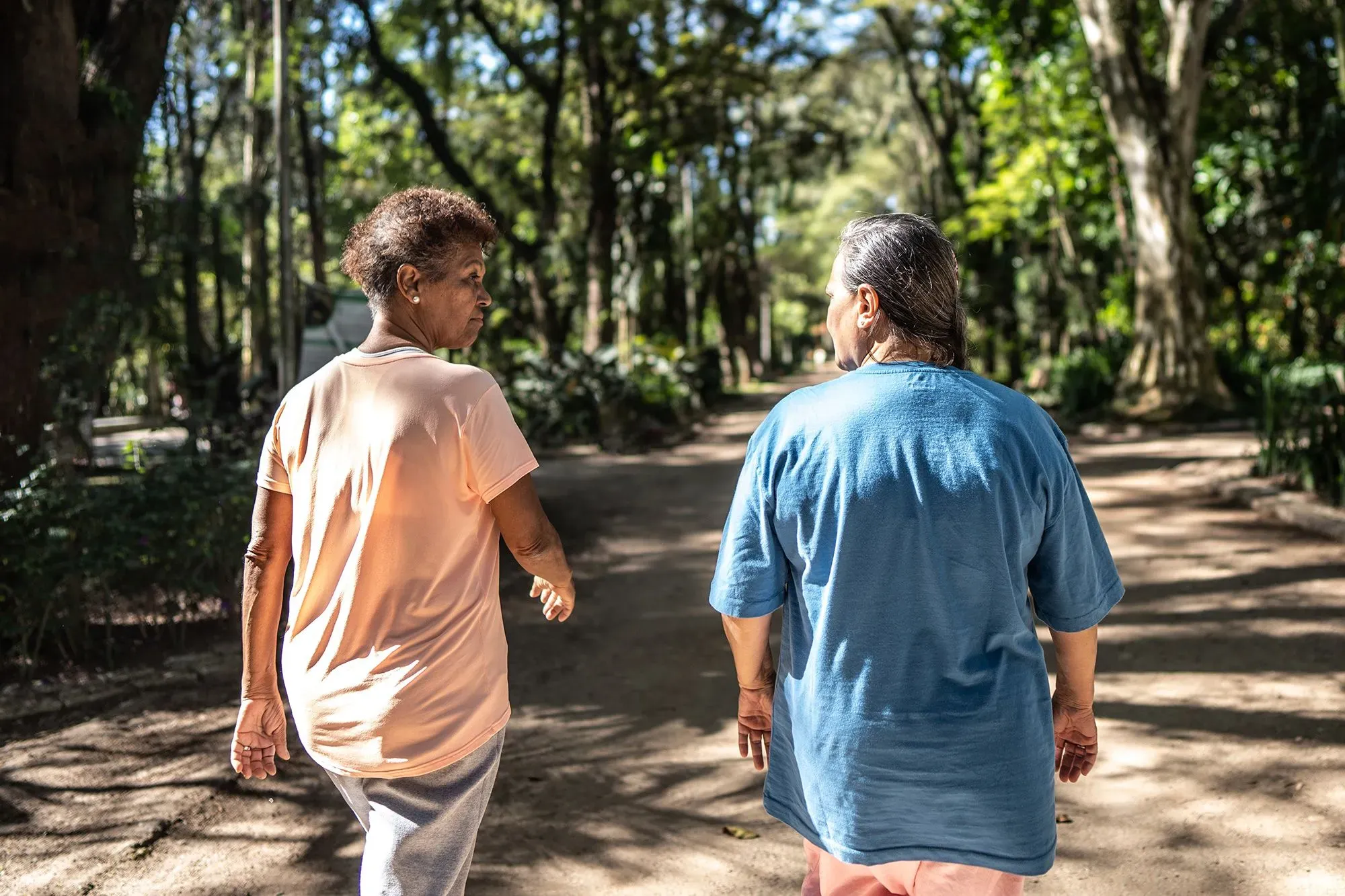 امرأتان مسنّتان تسيران معًا في حديقة، مما يعكس أهمية المشي اليومي في تعزيز الصحة العقلية وتقليل خطر التدهور المعرفي.