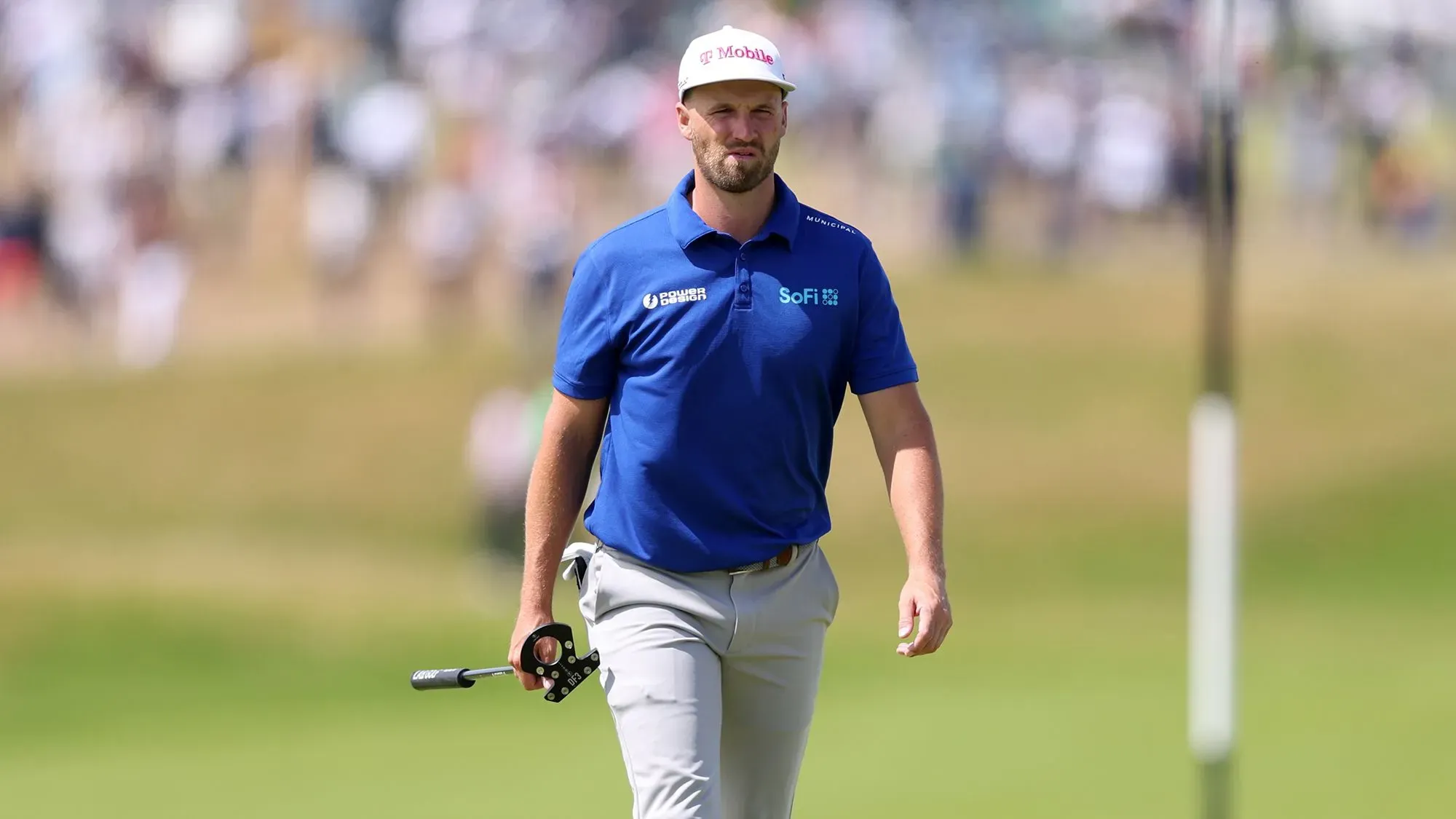 ويندهام كلارك يسير في ملعب الغولف، مرتديًا قميصًا أزرق، مع تعبير عن الأسف بعد حادثة إلحاق الضرر بخزانة في أوكمونت.