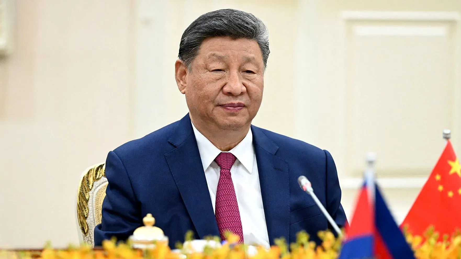 شي جين بينغ، الرئيس الصيني، يجلس في اجتماع رسمي، مع العلمين الروسي والصيني خلفه، في سياق زيارته لموسكو لتعزيز العلاقات.