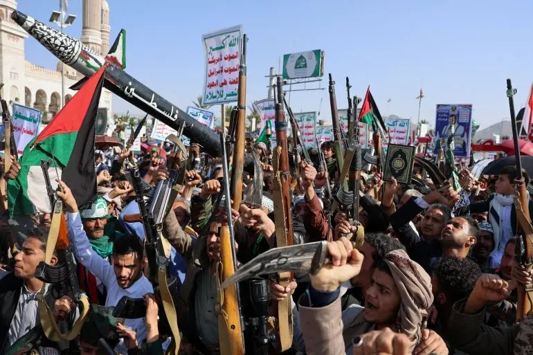 محتجون يحملون أسلحة ويرفعون لافتات خلال تظاهرة في اليمن دعماً لفلسطين، مع شعارات تعبر عن التضامن والمقاومة.