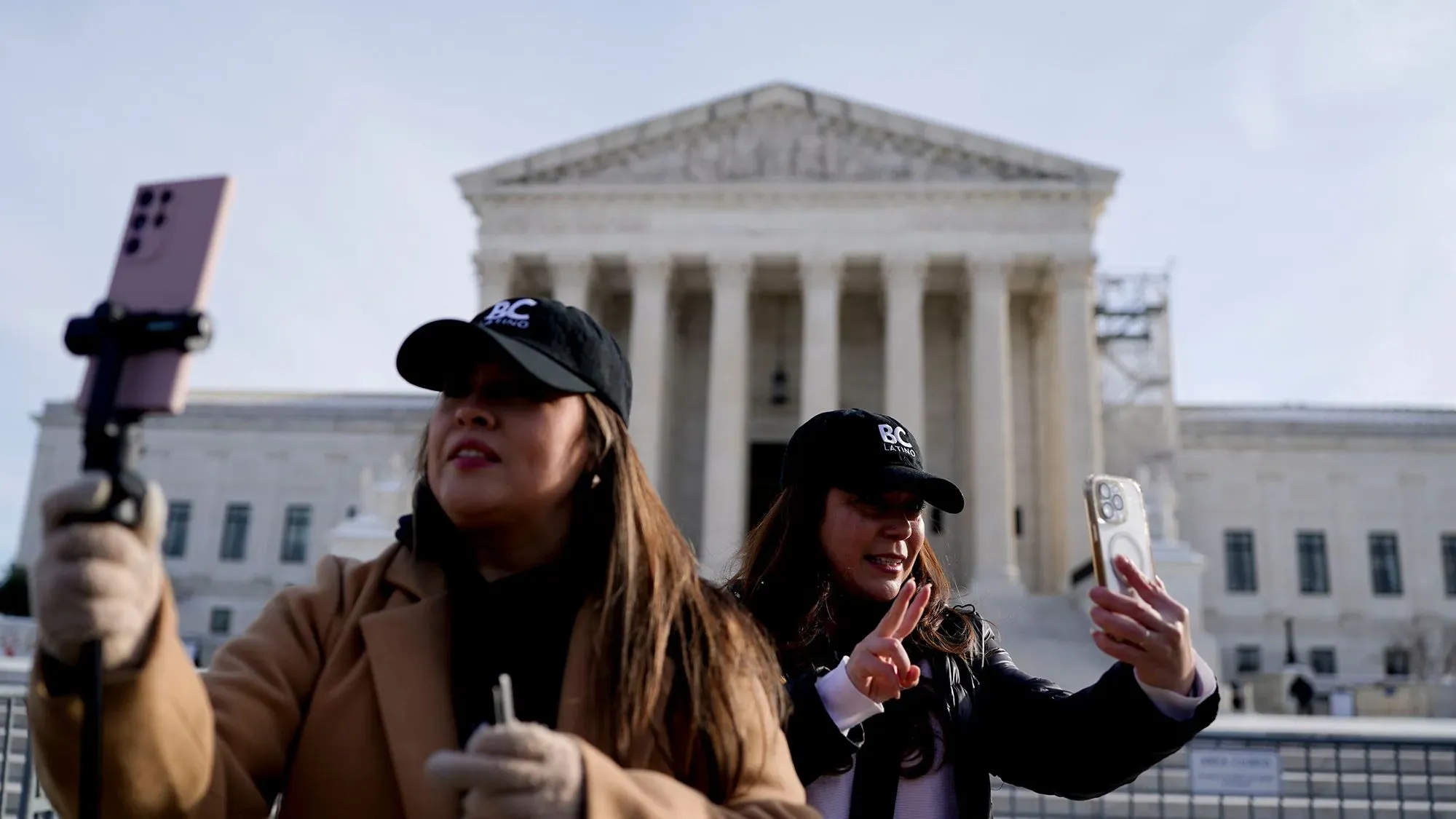 امرأتان ترتديان قبعات تحمل شعارًا، تتحدثان وتلتقطان صورًا أمام مبنى المحكمة العليا، في سياق مناقشات حول حظر TikTok في الولايات المتحدة.