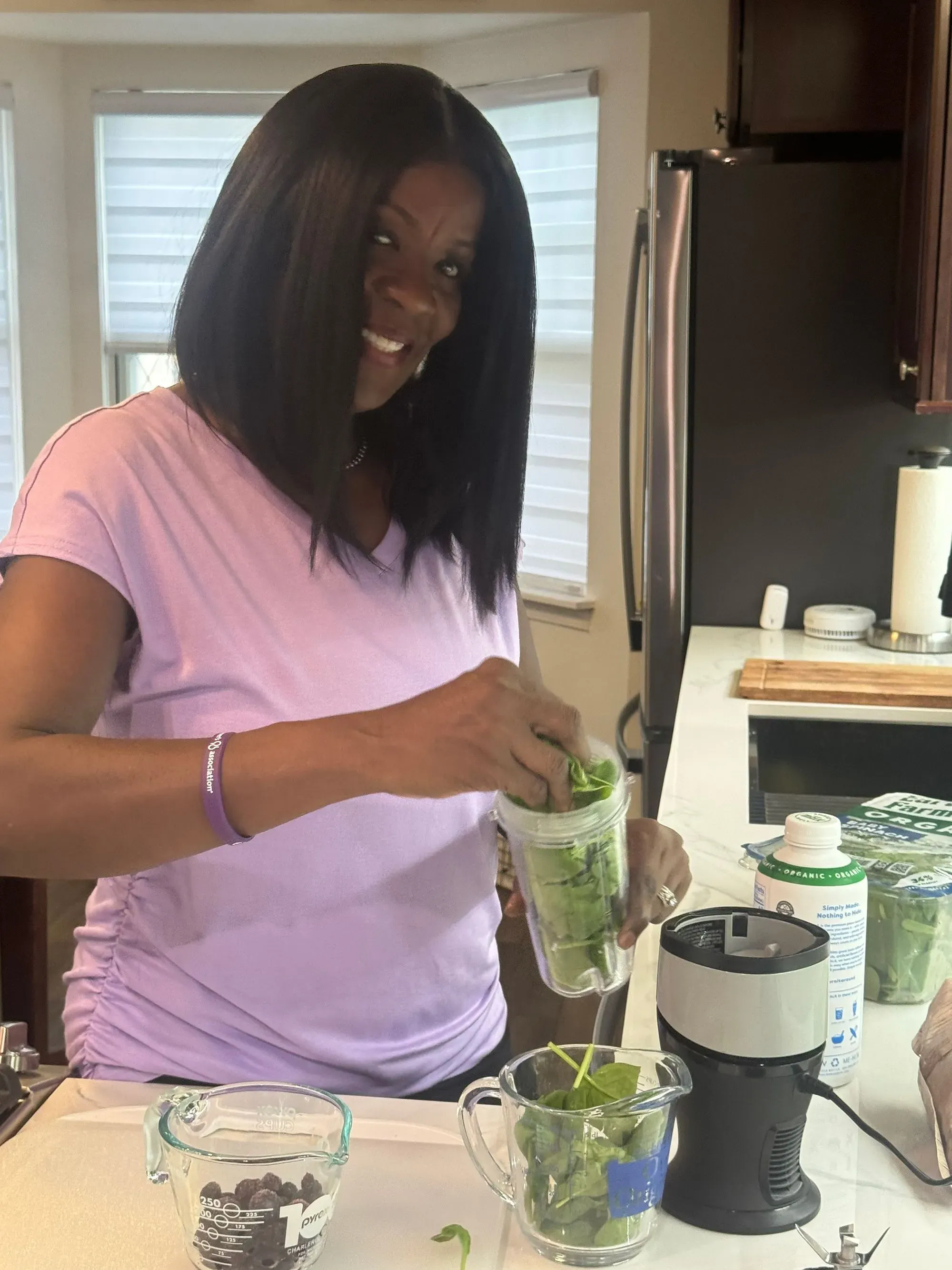 امرأة تضع السبانخ في خلاط لتحضير مشروب صحي، تعكس التزامها بنمط حياة صحي ضمن دراسة حول صحة الدماغ.