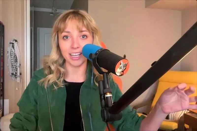 شابة تتحدث أمام ميكروفون في استوديو منزلي، تعبر عن آرائها حول السياسة والتغيير داخل الحزب الديمقراطي.