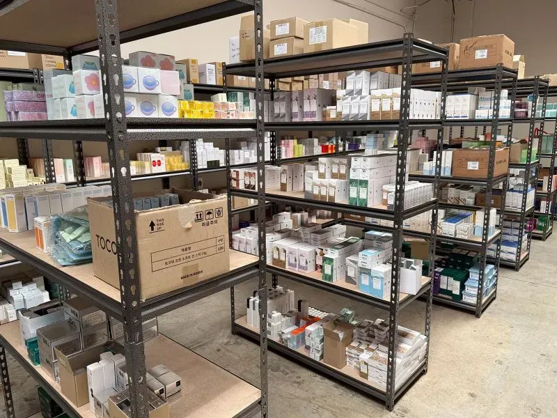 رفوف مليئة بعلب مستحضرات التجميل الكورية في مستودع، تعكس تزايد الطلب على هذه المنتجات في الولايات المتحدة وسط تغييرات تجارية.