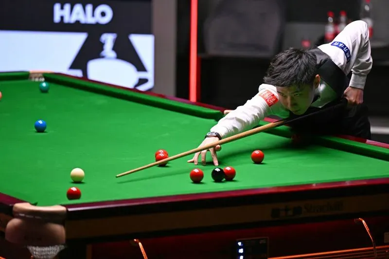 تشاو شينتونج، اللاعب الصيني، يسدد كرة في مباراة نهائي بطولة العالم للسنوكر، حيث حقق فوزًا تاريخيًا ضد مارك ويليامز.